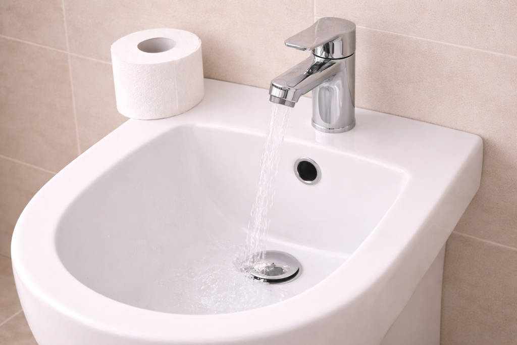 туалетная бумага на белом биде с напором воды